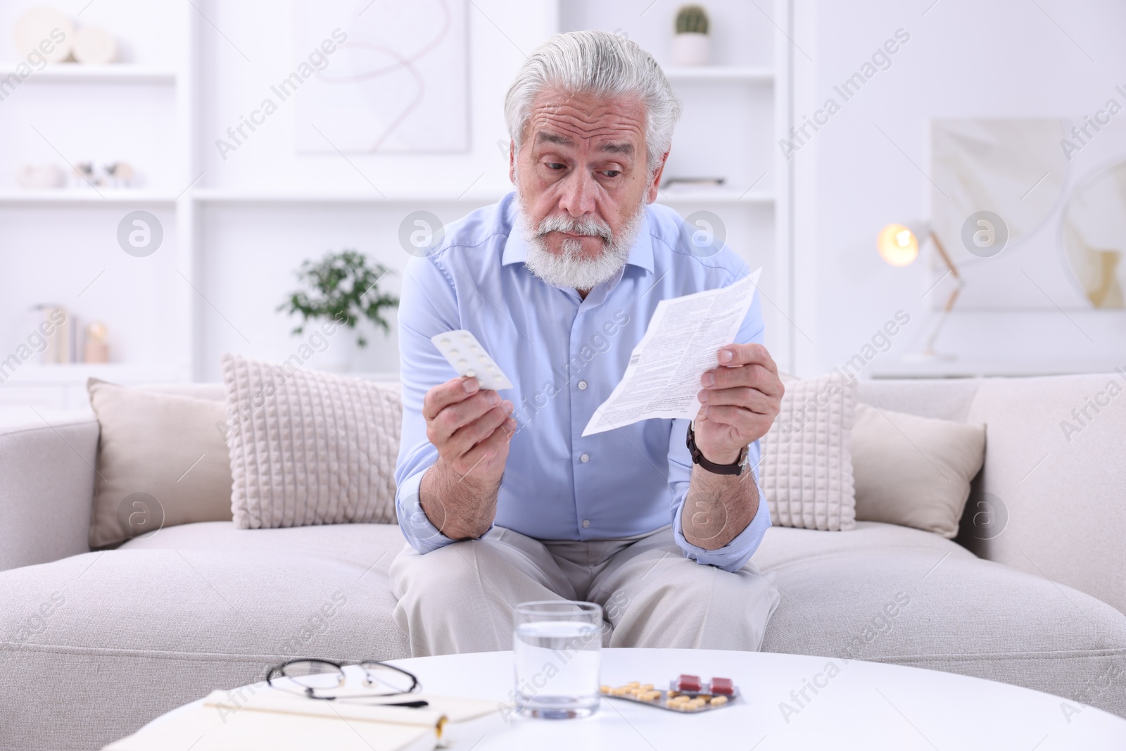 Photo of Senior man with pills reading medicine instruction at home