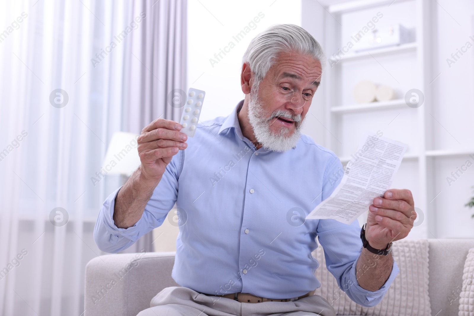 Photo of Senior man with pills reading medicine instruction at home