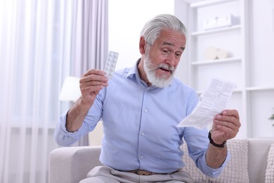 Senior man with pills reading medicine instruction at home