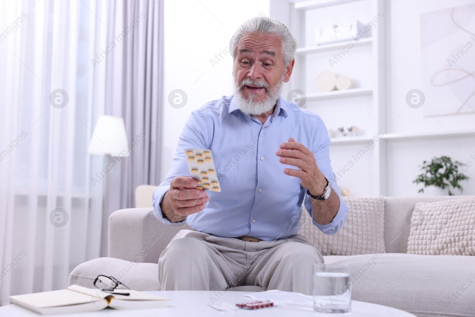 Photo of Senior man with pills on sofa at home