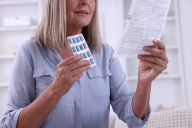 Senior woman with pills reading medicine instruction at home, closeup