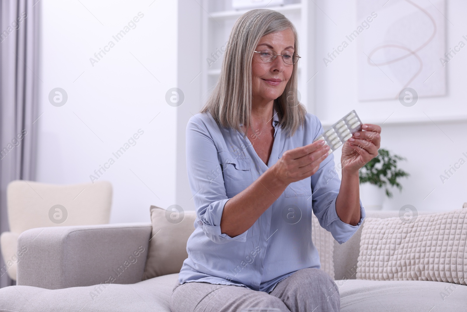 Photo of Senior woman holding blister with pills at home