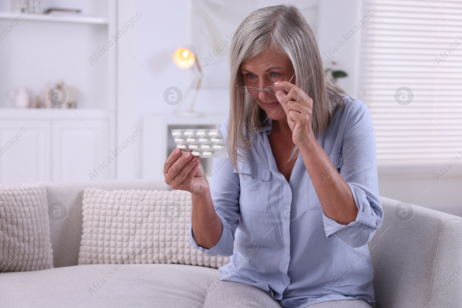 Photo of Senior woman holding blister with pills at home