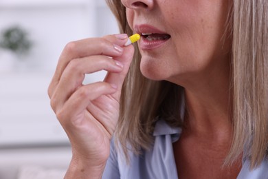 Photo of Senior woman taking pill at home, closeup