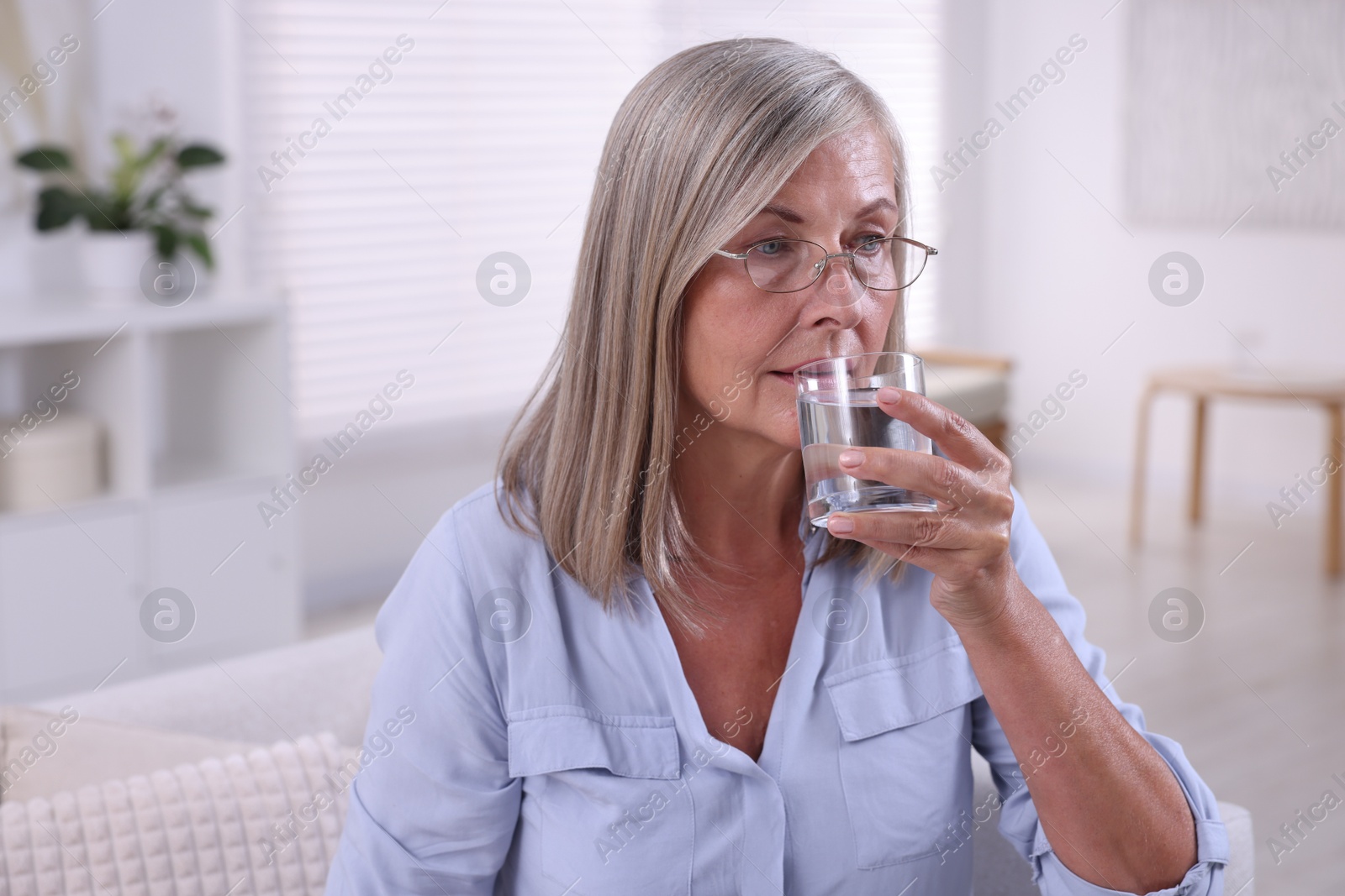 Photo of Senior woman in glasses drinking water at home