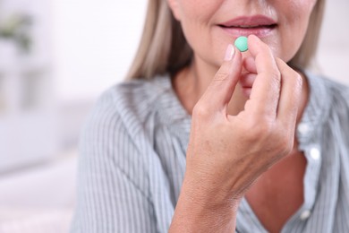 Senior woman taking pill at home, closeup