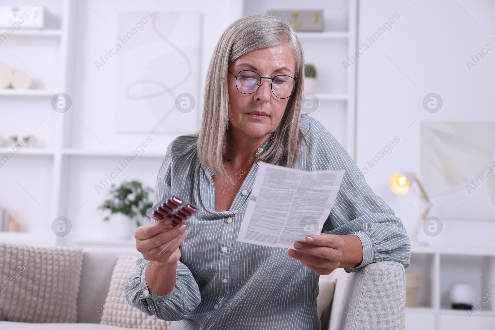 Photo of Senior woman with pills reading medicine instruction at home