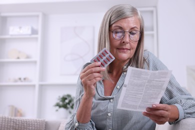 Senior woman with pills reading medicine instruction at home, space for text