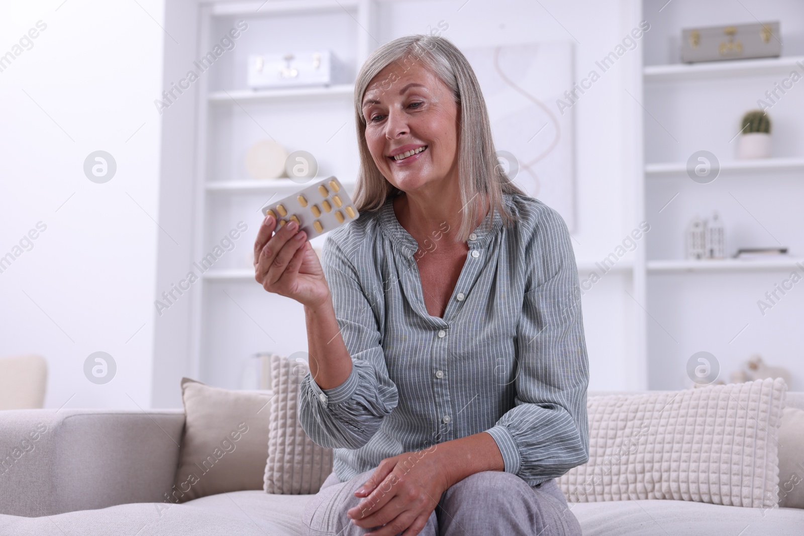 Photo of Senior woman holding blister with pills at home