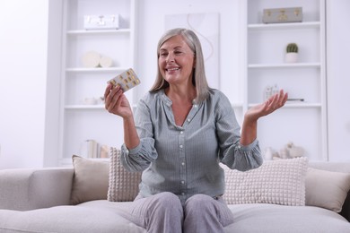 Senior woman holding blister with pills at home