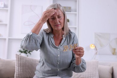 Senior woman holding blister with pills at home