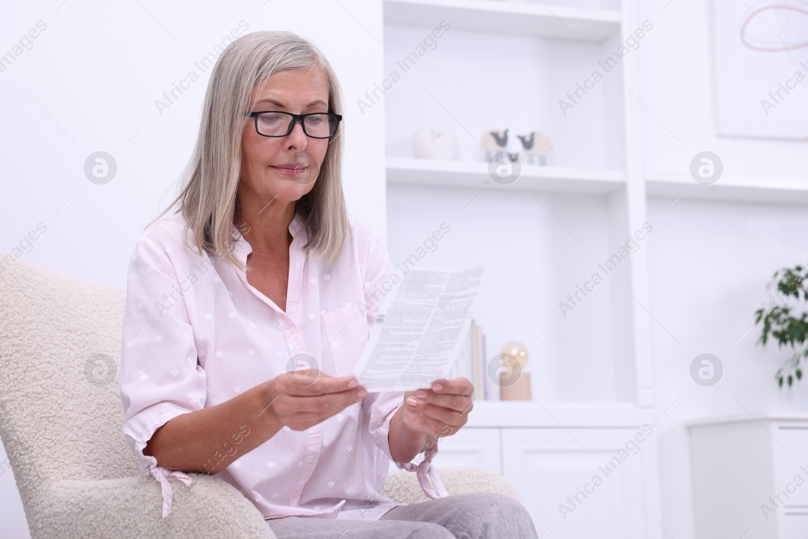 Photo of Senior woman reading medicine instruction in armchair at home