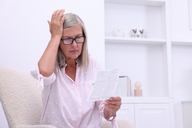 Photo of Senior woman reading medicine instruction in armchair at home