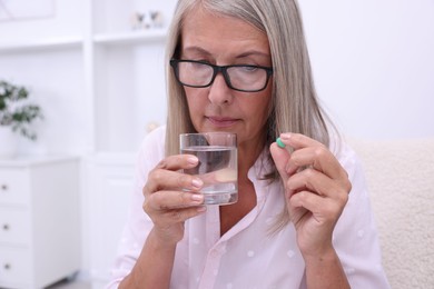 Photo of Senior woman with glass of water and pill at home