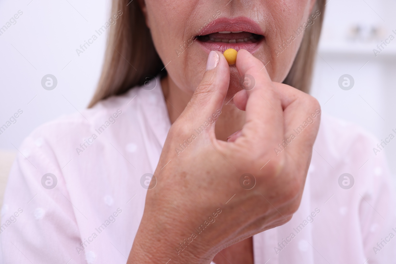 Photo of Senior woman taking pill at home, closeup