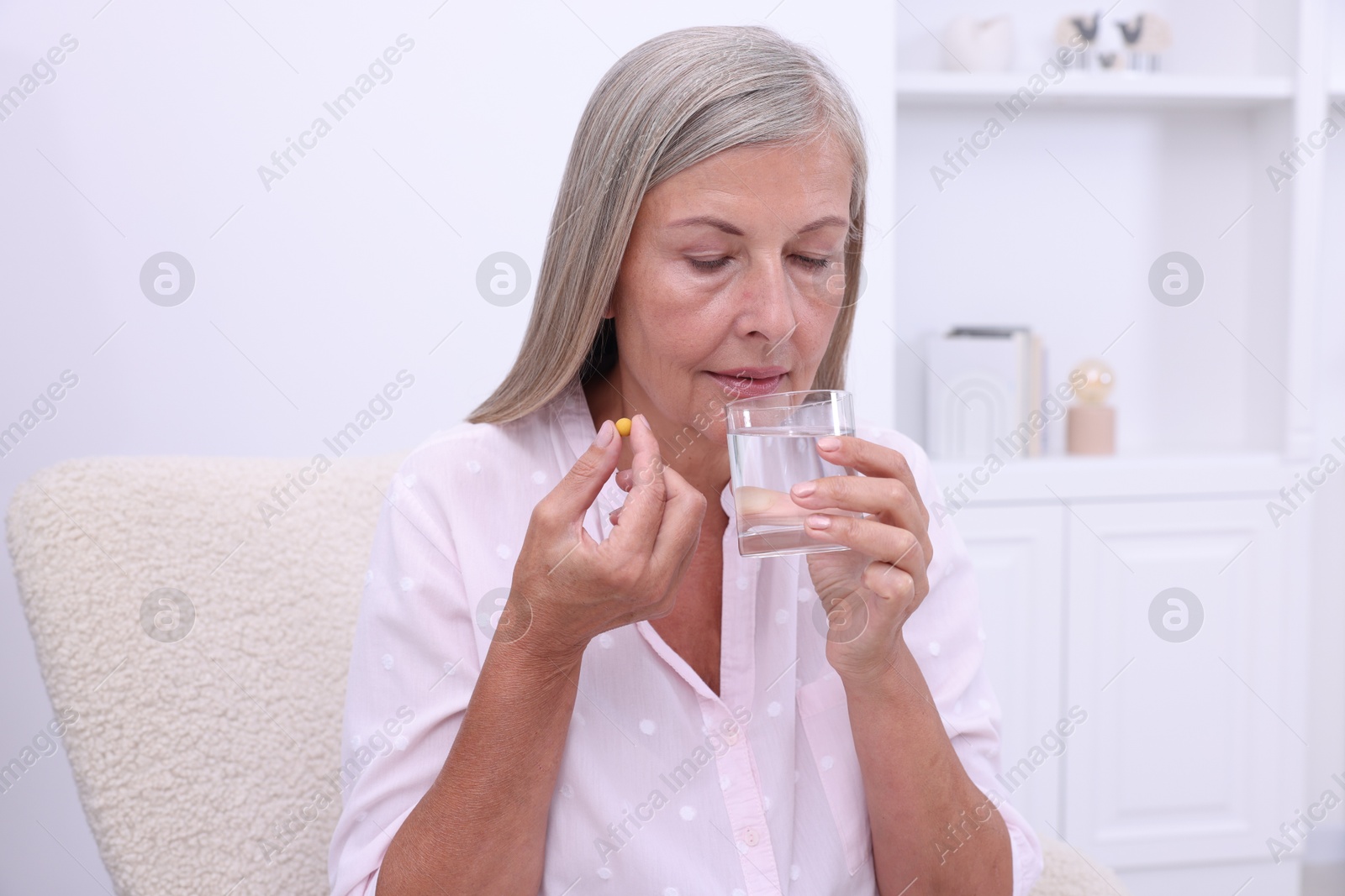 Photo of Senior woman with glass of water and pill at home