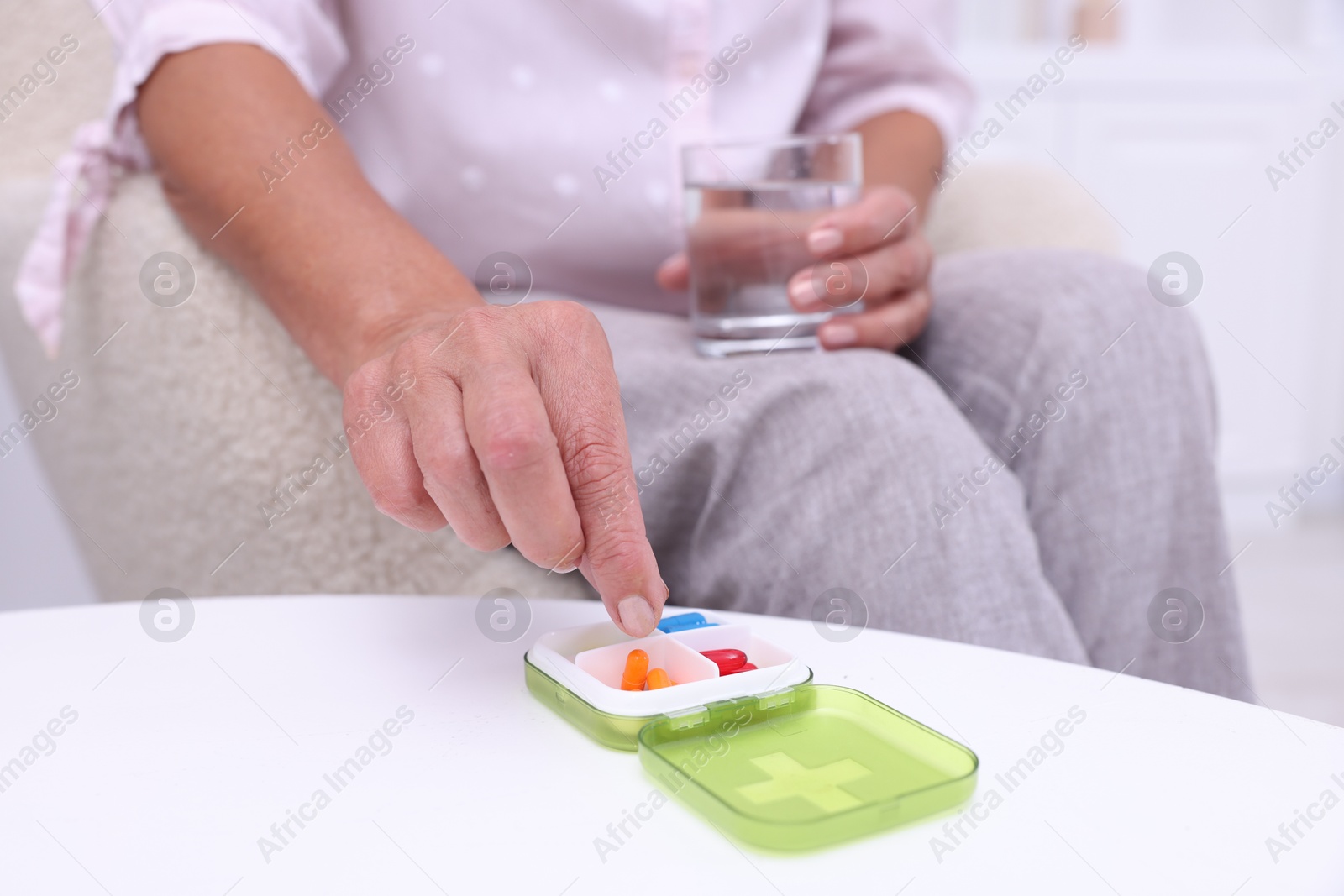 Photo of Senior woman taking pill from organizer at home, closeup