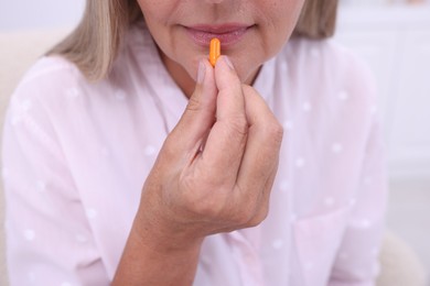 Senior woman taking pill at home, closeup