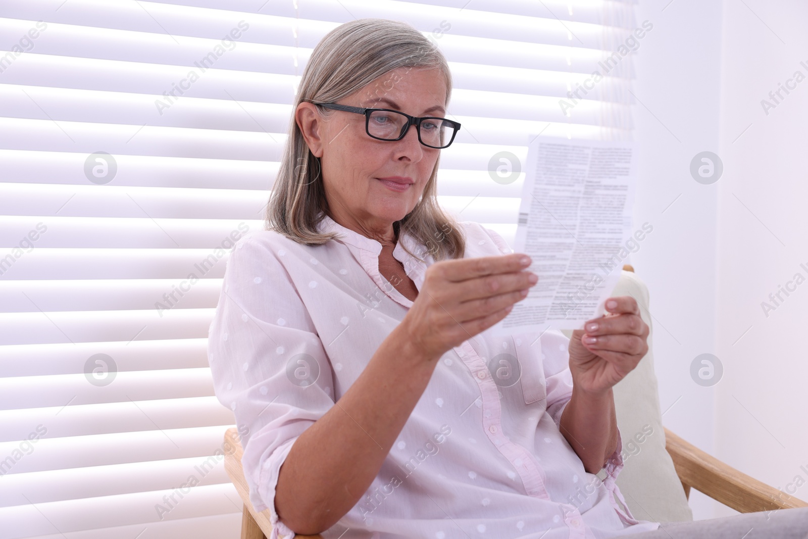 Photo of Senior woman reading medicine instruction in armchair at home