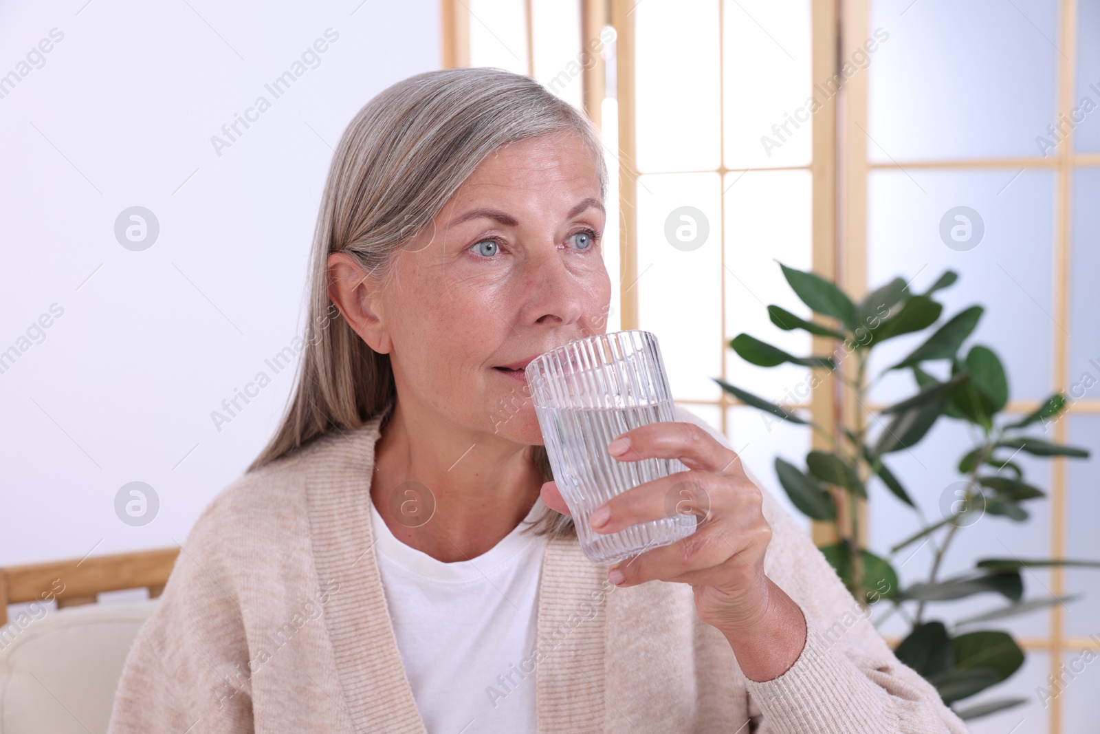 Photo of Beautiful senior woman drinking water at home