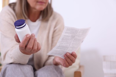 Senior woman with pills reading medicine instruction at home, closeup