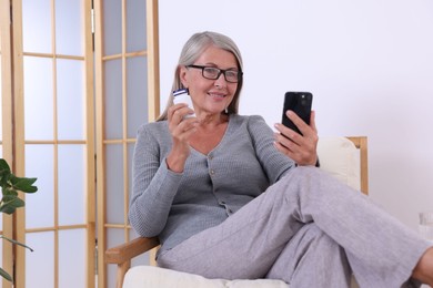 Photo of Senior woman with pills using smartphone at home