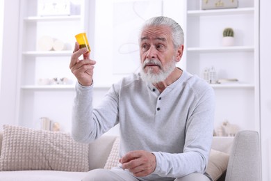 Photo of Senior man holding bottle with pills at home