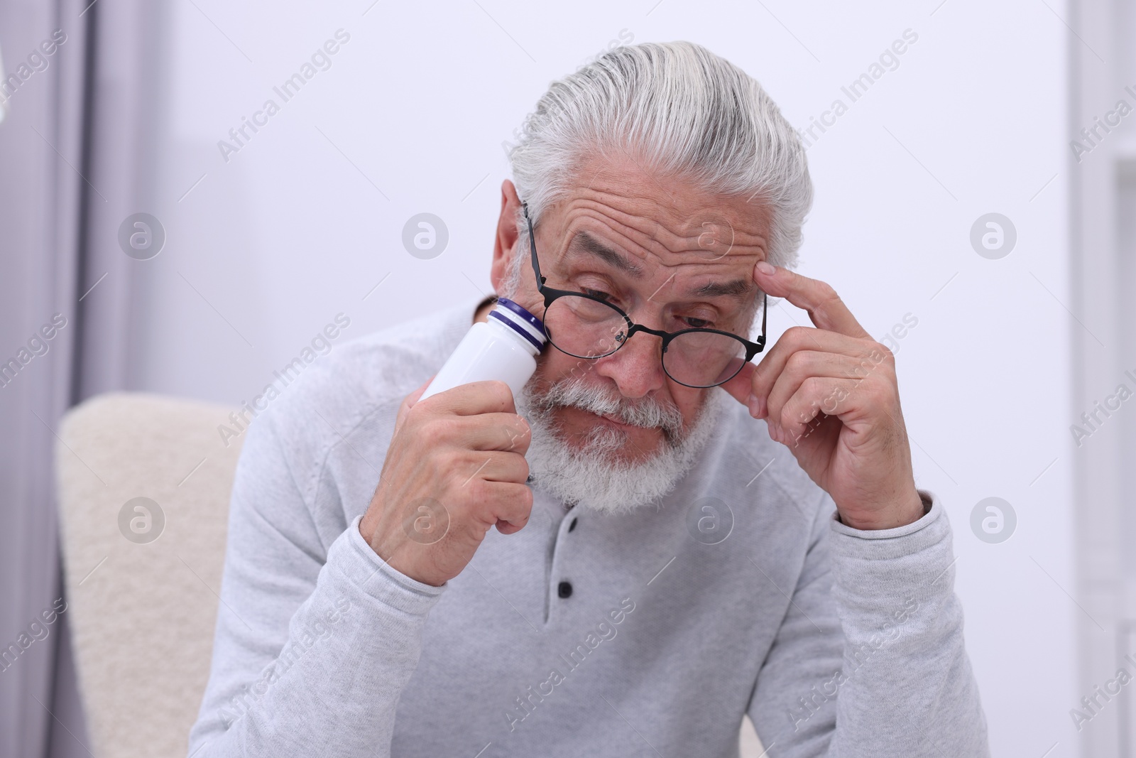 Photo of Senior man with bottle of pills at home