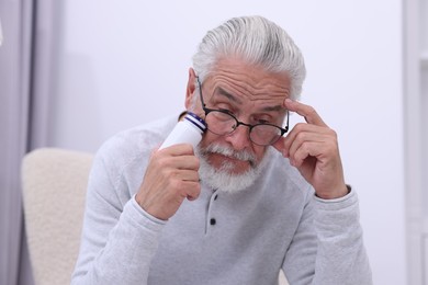 Senior man with bottle of pills at home