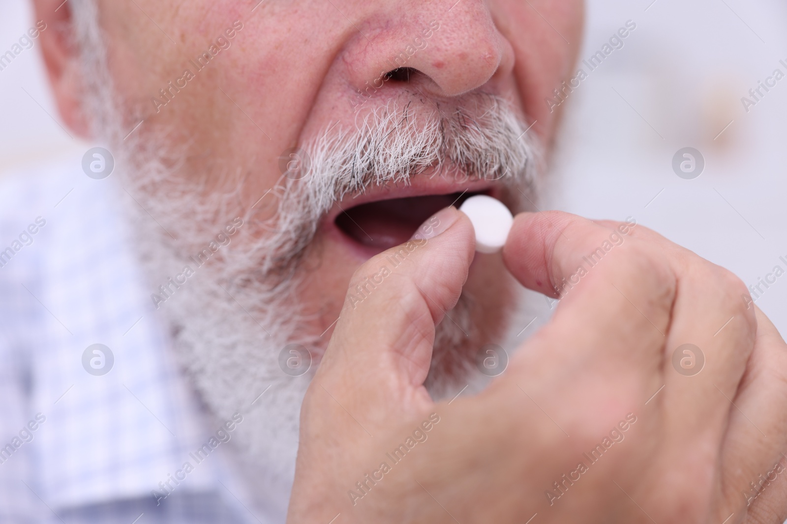 Photo of Senior man taking pill at home, closeup