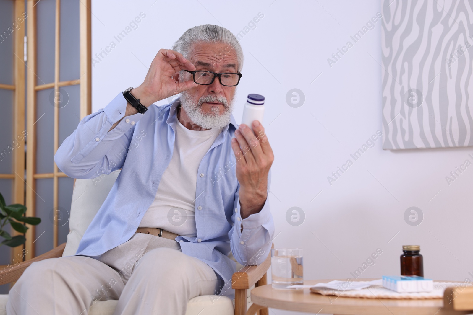 Photo of Senior man with bottle of pills at home