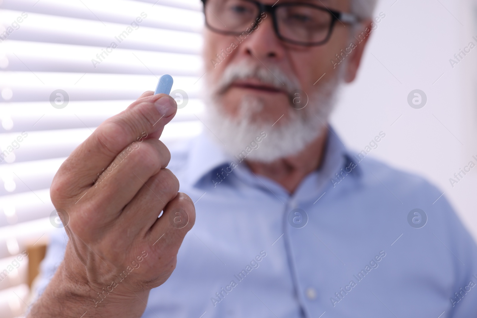 Photo of Senior man with pill at home, selective focus