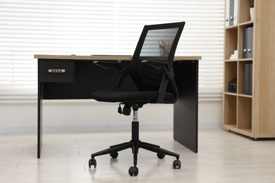 Black chair and wooden desk in office