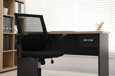 Black chair and wooden desk in office