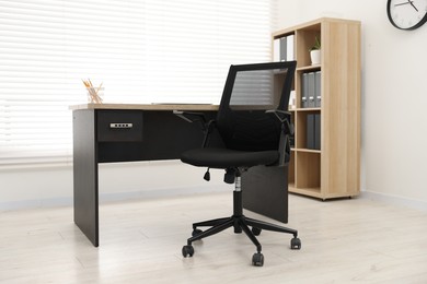 Black chair and wooden desk in office