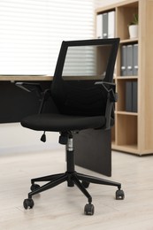 Black chair and wooden desk in office