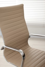 Stylish beige leather chair in office, closeup