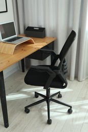 Black chair, laptop and desk in office