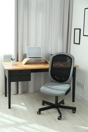 Photo of Grey chair, laptop and desk in office