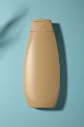 Photo of Bottle of shampoo on light blue background, top view