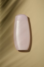 Photo of Bottle of shampoo on beige background, top view