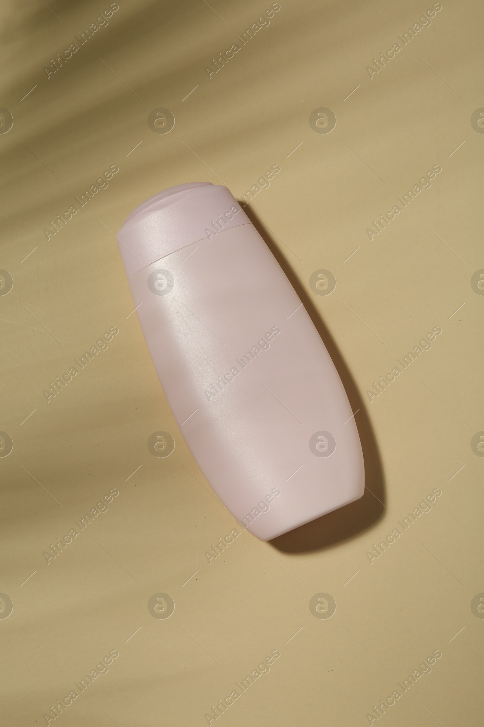 Photo of Bottle of shampoo on beige background, top view