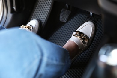 Photo of Woman in white shoes pushing on pedal of car brake, closeup