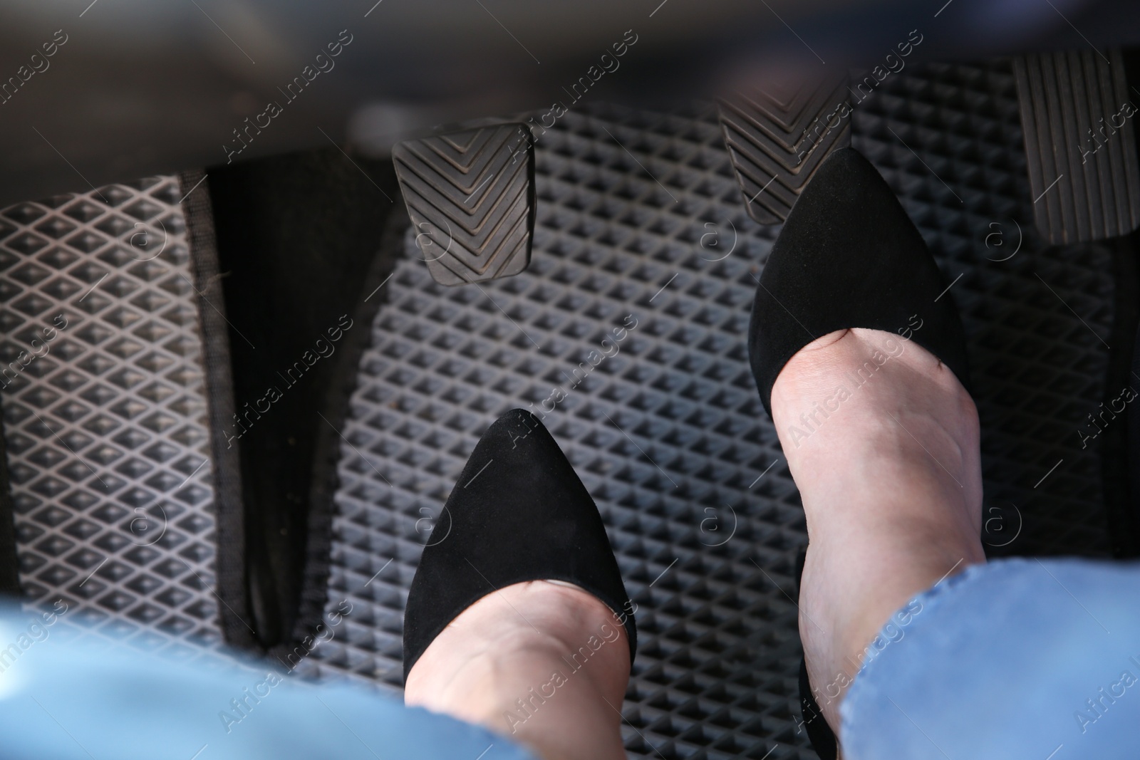 Photo of Woman in high heels pushing on pedal of car brake, closeup