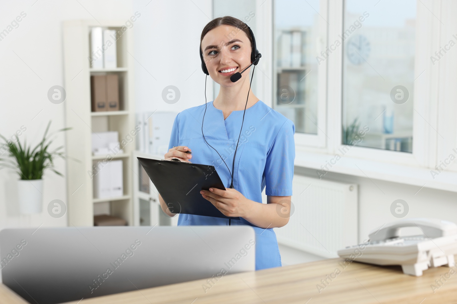 Photo of Professional receptionist working at wooden desk in hospital