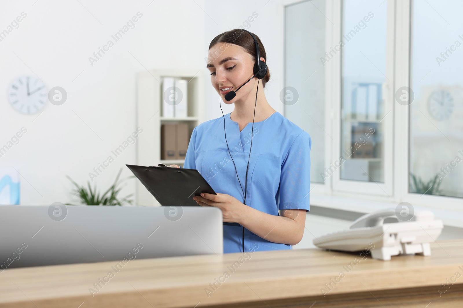 Photo of Professional receptionist working at wooden desk in hospital