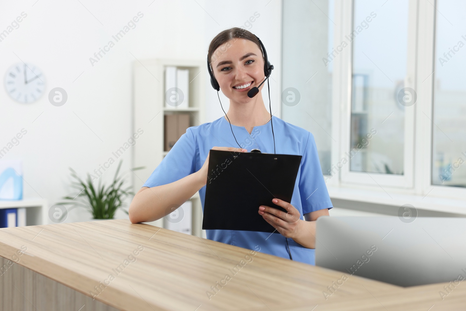 Photo of Professional receptionist working at wooden desk in hospital