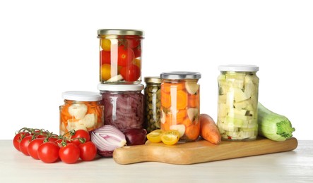 Photo of Different pickled products in jars and fresh vegetables on light wooden table against white background