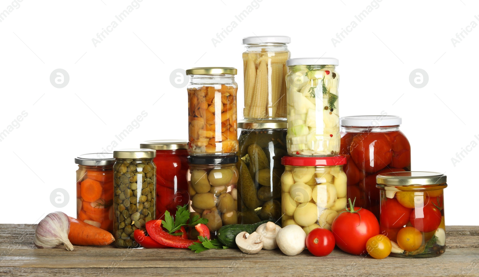 Photo of Different pickled products in jars and fresh vegetables on wooden table against white background