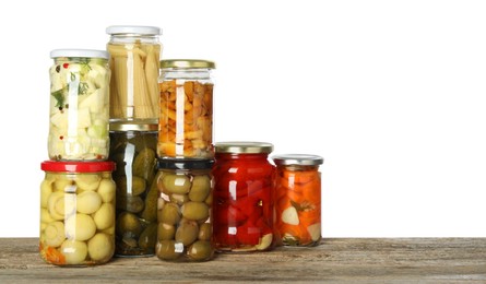 Photo of Different pickled products in jars on wooden table against white background. Space for text